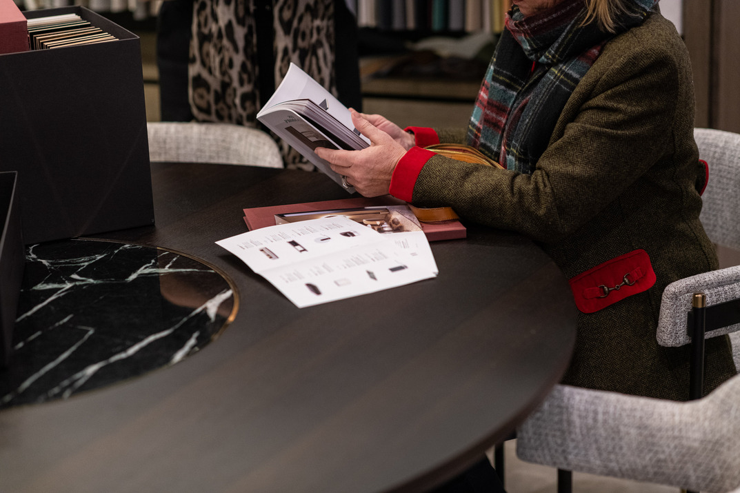 Interior designer reading Laskasas catalogue while seated on a chair