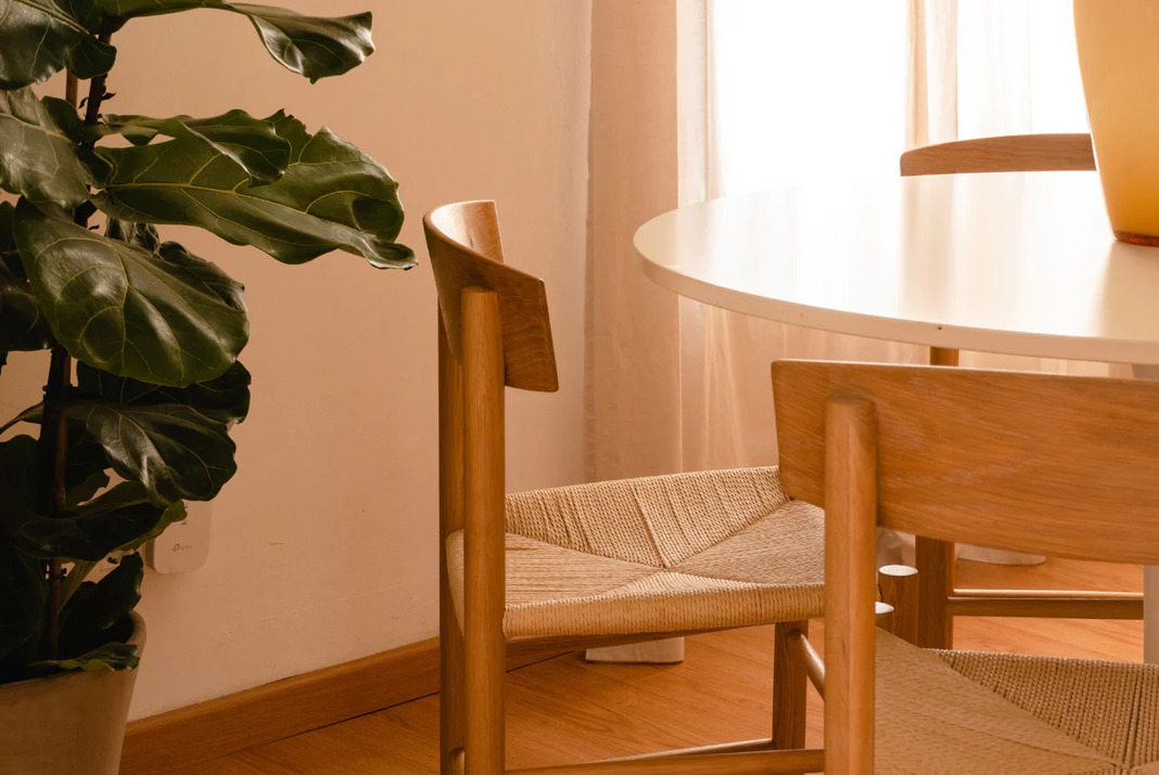 Cherry wood round dining table and dining chairs next to a flower pot