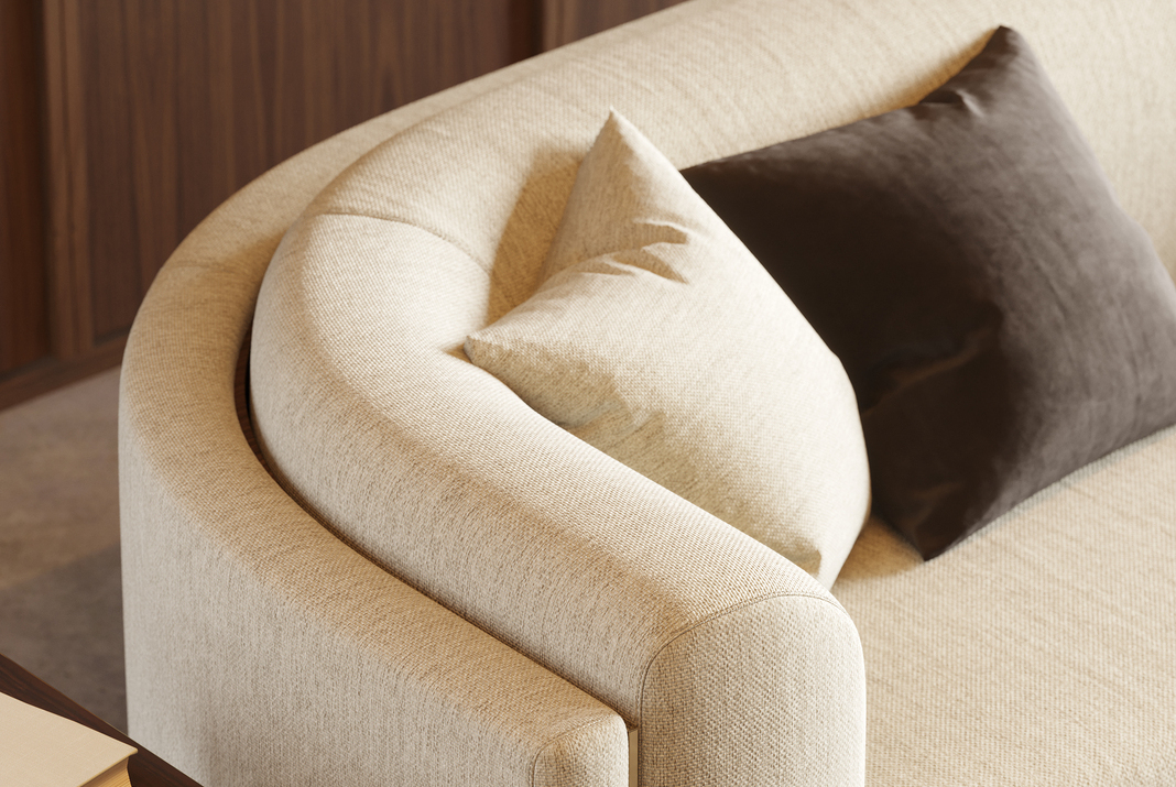 White curved sofa with two pillows next to a side table.