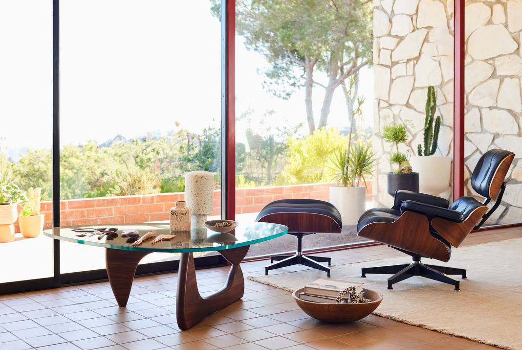 Eames lounge armchair with ottoman and Noguchi coffee table in a living room with a view