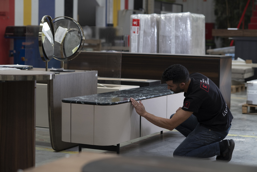 Craftsman in furniture factory touching a TV cabinet