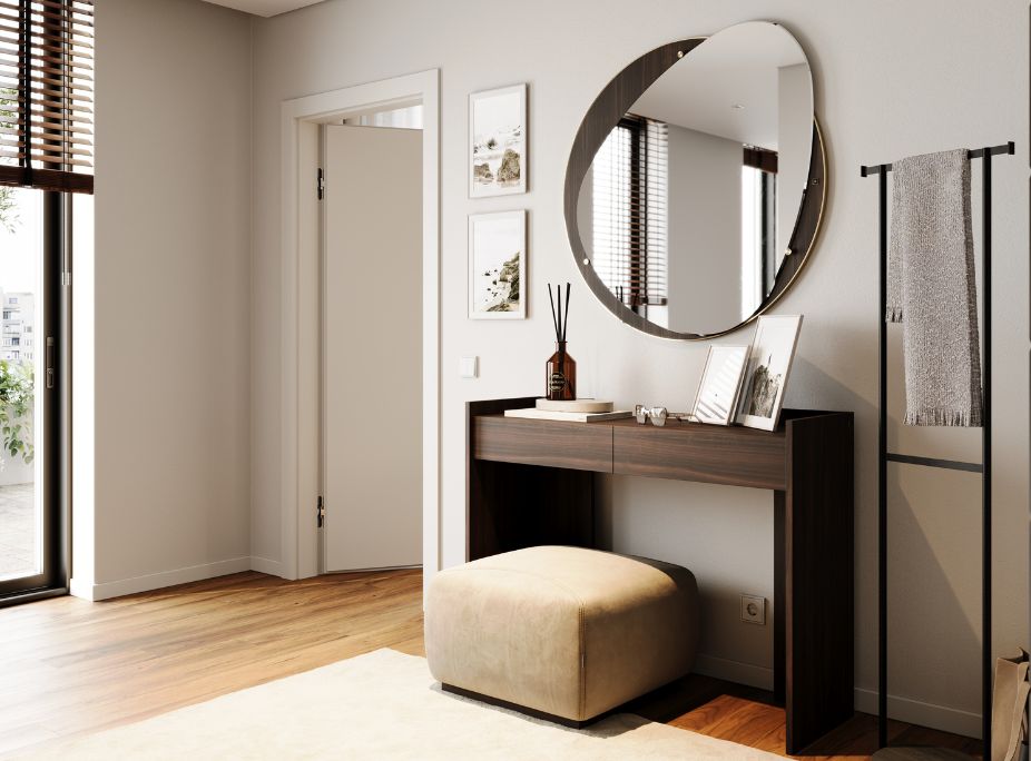 A dark wood console table with a linear profile, an irregular-shaped wall mirror, and a beige puff.