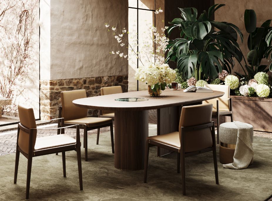 An oval wooden dining table surrounded by leather-upholstered chairs, positioned against a feature stone wall with plants.