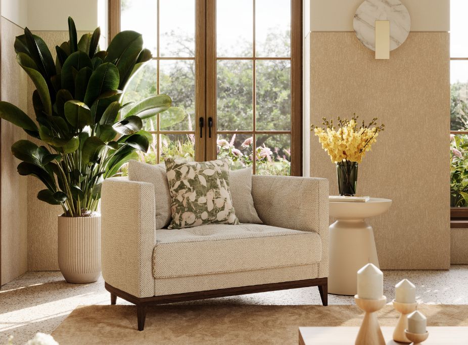 An armchair in light textured fabric with a green leaf-patterned cushion, placed next to a large indoor plant.