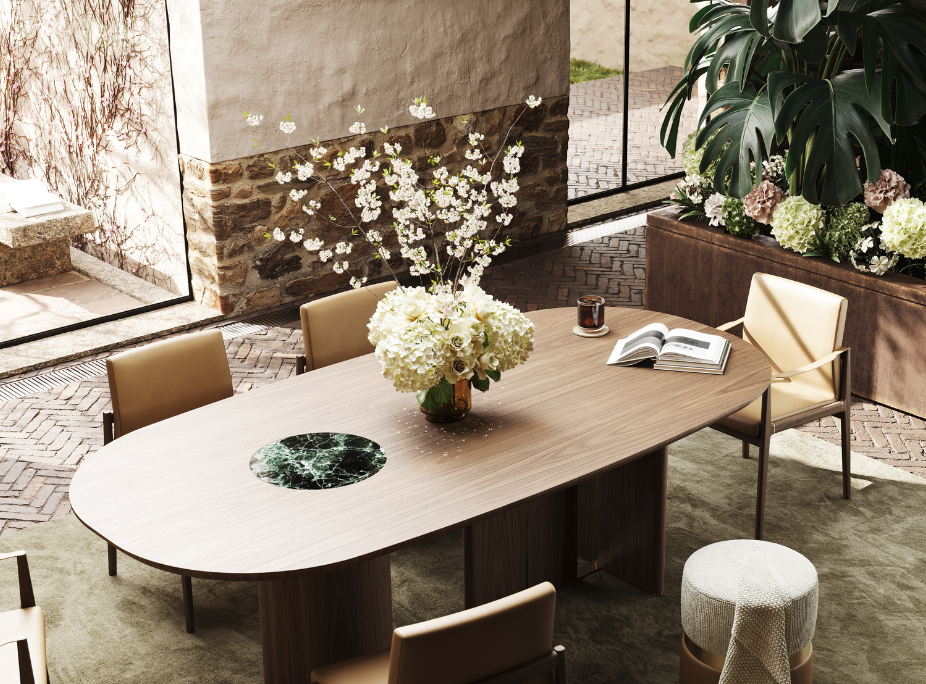 Plano de detalhe de uma mesa de jantar oval em madeira com detalhe central em mármore verde escuro, que destaca o design exclusivo da peça. Um arranjo de flores brancas adiciona frescura sobre a mesa. Funcionalidade completada com cadeiras em pele e puff em tecido.